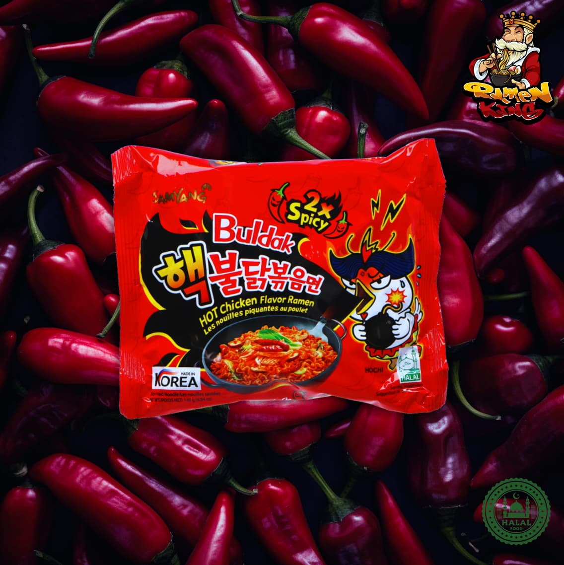 Ein ungeöffnetes Paket von Buldak 2x Spicy Ramen auf einem roten Hintergrund. Die Verpackung hat das Bild eines cartoonisierten Huhns, das Feuer spuckt, und koreanische Schriftzeichen, die die Schärfe des Produkts betonen.