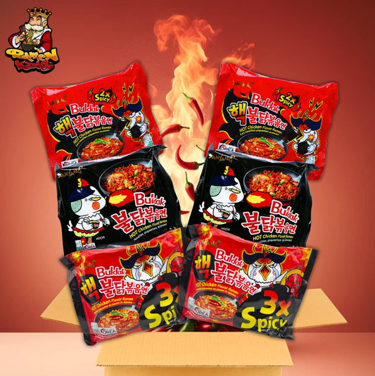 Das Bild zeigt eine Auswahl sehr scharfer Ramen-Nudelpackungen mit der Aufschrift "2x Spicy" und "3x Spicy". Die Packungen sind leuchtend rot mit Abbildungen von Hähnchen und Flammen, was ihre Schärfe betont. Im Hintergrund sind Flammen illustriert, und das Logo "Ramen King" ist erkennbar. Es ist eine Cartoon-Figur zu sehen, die auf die koreanische Herkunft der Nudeln hinweist.